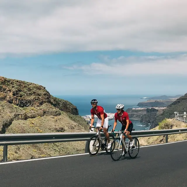 Two cyclists riding on a coastal mountain road